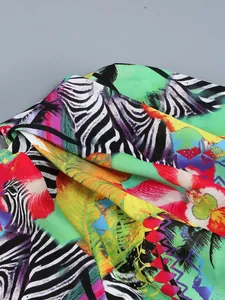 Close-up of tropical zebra print fabric on a vibrant asymmetric ruffled resort dress.