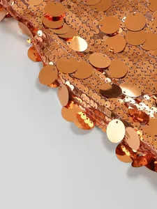 Primer plano de las brillantes lentejuelas circulares naranjas en el detalle de un vestido