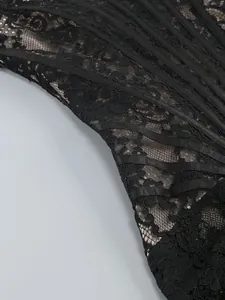 Close-up of intricate black lace and vertical boning detail on elegant corset dress.