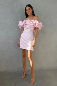 Detalle de elegante vestido corto rosa con volantes y hombros caídos en modelo