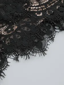 Close-up of elegant black floral lace fabric with delicate eyelash fringe detail