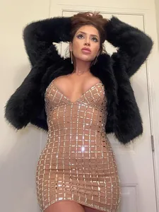 Detail view of a sequined nude bodycon dress paired with a black faux fur jacket.