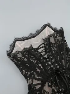 Detail view of a black floral lace corset with ribbon lace-up back and metal eyelets.
