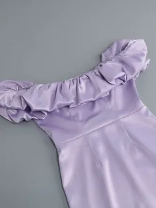 Detalle de un vestido morado con hombros descubiertos y volantes en tela satinada brillante