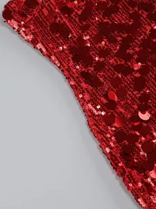 Primer plano detallado de lentejuelas rojo rubí brillantes en un elegante vestido de noche.