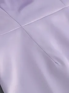 Primer plano de la elegante tela de un vestido lavanda con finas líneas de costura