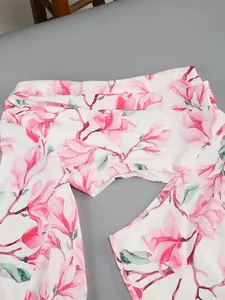 Close-up of pink magnolia floral print on white elegant summer vacation dress