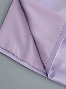 Primer plano de la textura de la tela lavanda y detalles de costura de un vestido