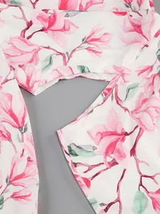 Close-up detail of a white dress featuring elegant pink magnolia floral prints and sleeve seam