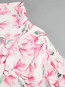 Close-up view of the pink floral print and delicate ruffle detail on the white dress