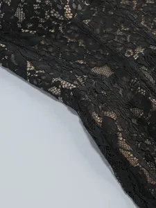 Close-up detail of black floral lace fabric with nude lining for an elegant evening dress.