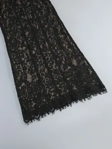 Detailed macro shot of delicate black floral lace fabric with eyelash trim and nude lining.
