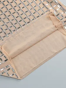 Close-up detail of heavy silver rhinestone pattern on beige mesh dress fabric.