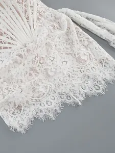 Detailed close-up of intricate white floral lace and eyelash trim on elegant corset dress