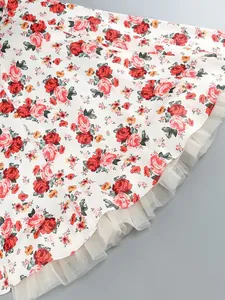 Detail of white floral dress with red rose print and layered white tulle hemline