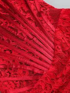 Close-up detail of red floral lace and satin corset ribbing on an elegant dress.