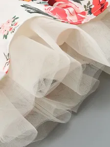 Close-up detail of multi-layered white tulle mesh skirt on elegant floral dress.