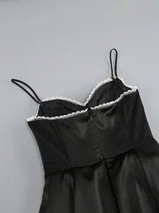 Close-up detail of a black satin corset dress featuring elegant white lace trim