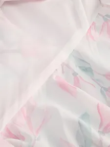Macro detail view of elegant white fabric featuring pink floral prints and ruffled edges