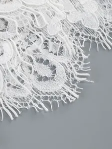 Close-up detail of elegant white sheer lace fabric with intricate floral embroidery patterns