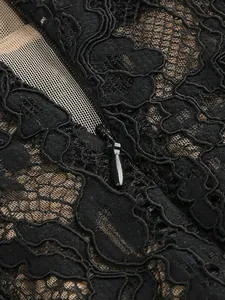 Detailed view of the invisible zipper and intricate black lace texture on the dress
