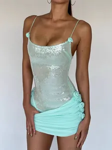 Detail van een mintgroene paillettenjurk met delicate bloemaccenten en gerimpelde zoom
