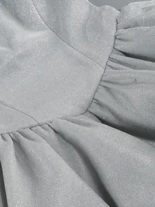 Dettaglio macro che mostra il tessuto glitterato argento e la texture pieghettata dell'abito da sera