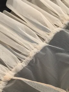 Detailed macro shot of elegant beige ruffled tulle fabric on a black evening dress