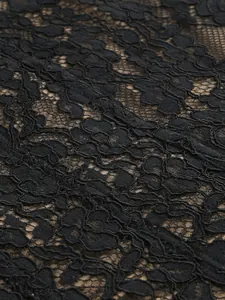 Intricate close-up view of elegant black floral lace texture on mesh evening dress