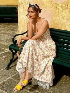 Elegant floral print slip dress with lace hem worn by a model in a sunlit garden.