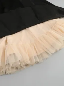 Close-up detail of the layered voluminous champagne mesh hem on an elegant black dress