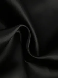 Macro view of premium black satin fabric texture showing elegant folds and soft luster.