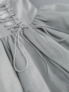 Primo piano del tessuto glitterato argento e del dettaglio stringato sul retro dell'abito