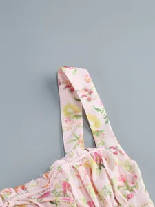 Macro view showing the shoulder strap and lace trim of a pink floral camisole dress