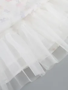 Macro detail close-up of white tulle mesh ruffles and floral print dress hemline