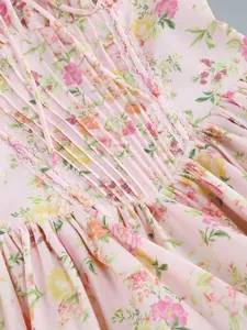 Detailed close-up of delicate lace trim and pleats on a pink floral camisole dress.