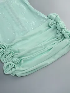 Detail van een mintgroene paillettenjurk met elegante chiffon plooien en rozetten