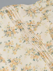Close-up detail of pleated fabric on a yellow floral print summer vacation dress.