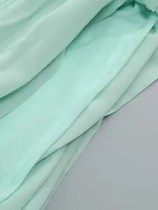 Close-up van de fijne mintgroene chiffon stoftextuur en de voering van mesh.