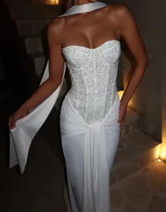 Detail of white sequined strapless maxi dress with corset bodice and draped skirt