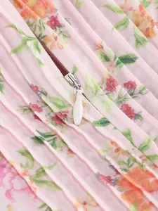 Close-up macro view of pink floral pleated dress with invisible water-drop zipper detail