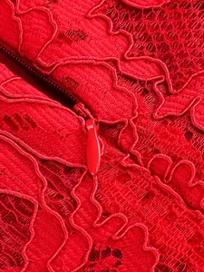 Close-up detail of red floral lace fabric and invisible zipper on a formal dress