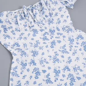 Close-up detail of a French floral dress with blue flowers and a bow-tie neckline.