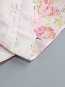 Macro detail of pink floral dress featuring pleated textures and delicate hem stitching.