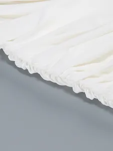 Close-up detail of white pleated dress fabric showing high-quality gathered hem craftsmanship