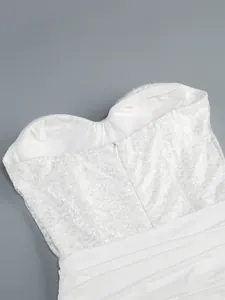 Close-up detail of white sequined strapless bodice with pleated skirt and zipper