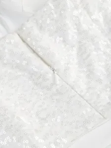 Macro detail view of white sequin fabric and invisible zipper on elegant evening gown