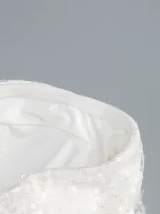 Detailed close-up of white sequined tube dress neckline and shimmering fabric texture.