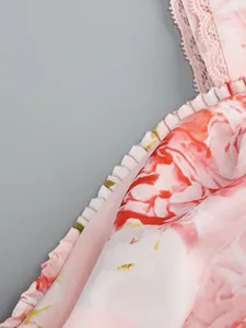 Macro view of pink rose floral print satin fabric featuring delicate ruffle edge and lace detail