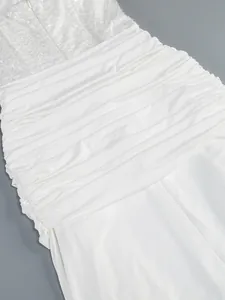 Close-up detail of white sequined strapless maxi dress with elegant ruched fabric texture.